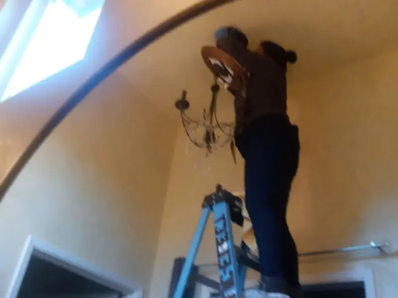 Electrician installing a chandelier in a Pasco residence
